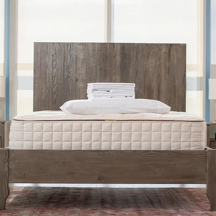 Bedroom view Naturepedic Organic Cotton Percale Sheets + Pillowcases stacked on mattress 